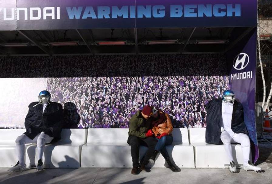 Due tifosi si concedono un attimo di relax su una panchina riscaldata mentre aspettano di guardare il Superbowl. Afp